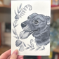 A photo of a hand holding an illustration of a dog in black and white ink