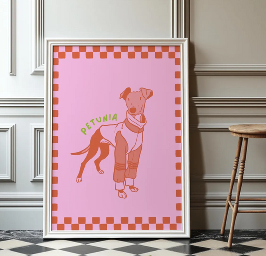 Framed artwork of a stylized line art dog illustration on a pink background and checkered boarder with 'Petunia' text, leaning against a wall.