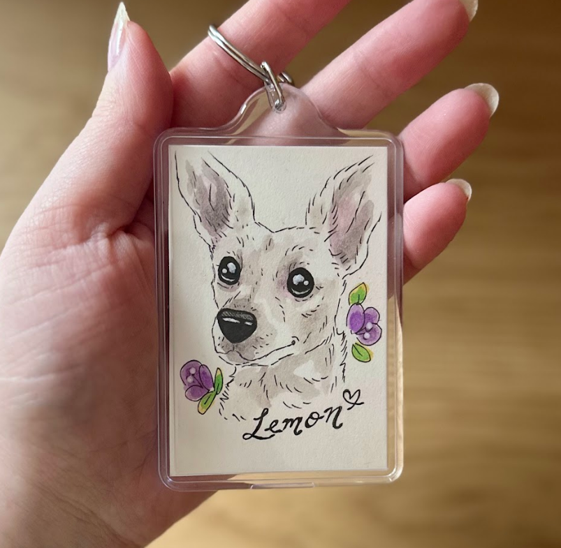 Keychain with a dog illustration and the name 'Lemon' held in a hand.