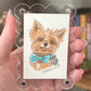 Illustration of a dog with a bow tie on a card held by a hand.