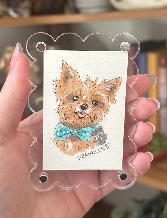 Illustration of a dog with a bow tie on a card held by a hand.