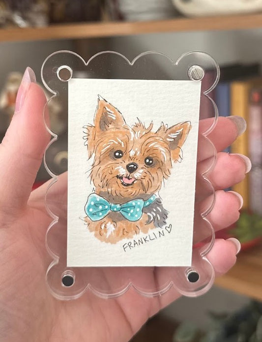 Illustration of a dog with a bow tie on a card held by a hand.