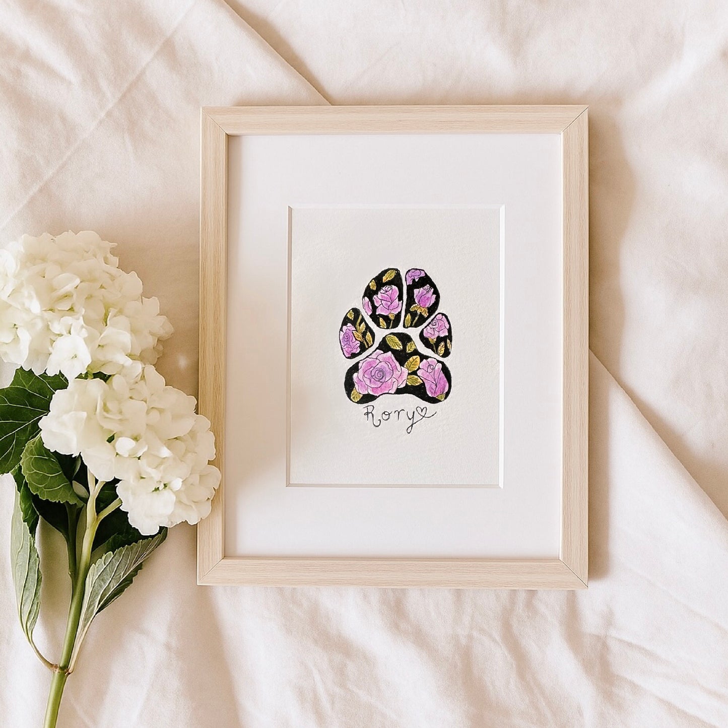 Framed artwork of a floral paw print with 'Rory' on a light background